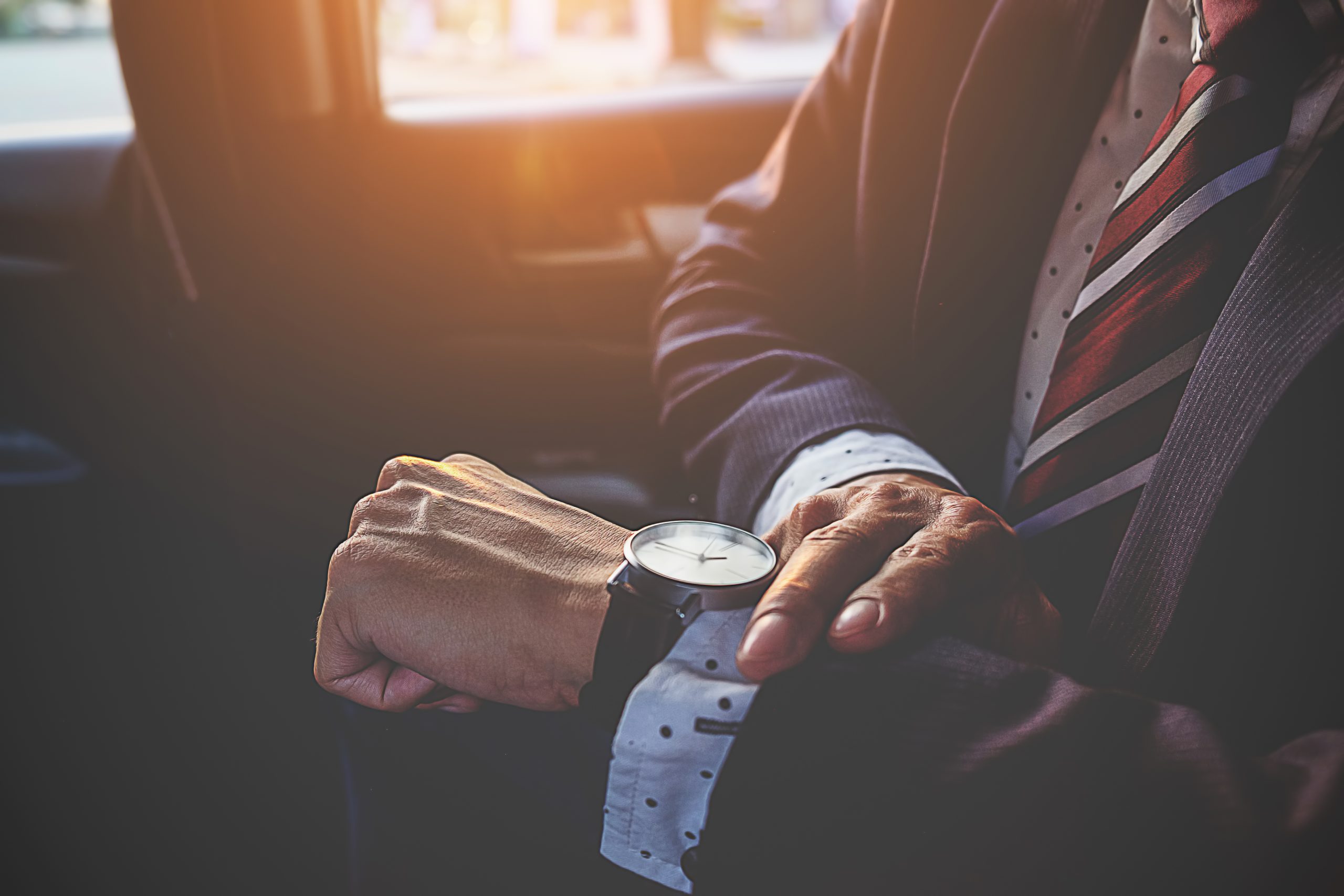 Businessman looking at the time on his wrist watch in car. Business concept.