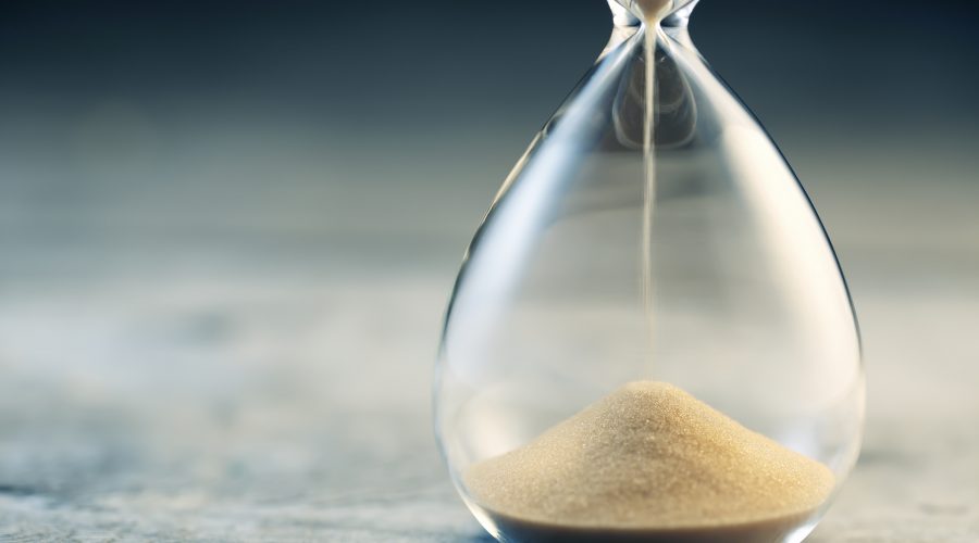 Flowing hourglass on wooden table; Twilight blue